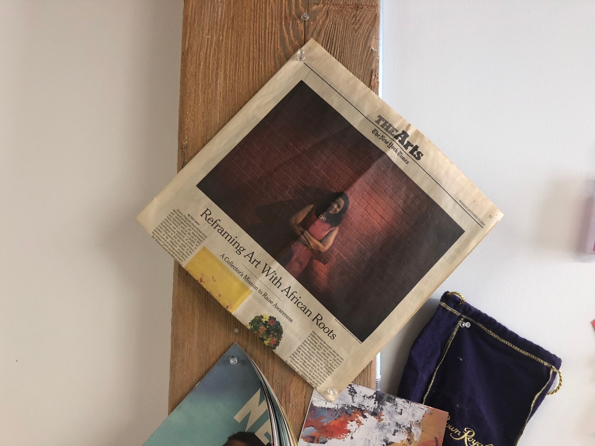 Process photograph from the 2018 offsite rendition of Curatorial Exchange with Art Institute Chicago. A copy of the arts section of the October 17, 2016 New York Times is pinned to a wooden plank on a white wall. The lead article reads ‘Reframing Art With African Roots: A Collector’s Mission to Raise Awareness’.

