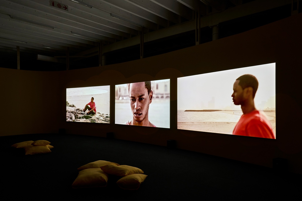Installation photograph from the ‘Risk’ exhibition in A4’s Gallery. On the right, John Akomfrah’s three-channel video installation ‘Four Nocturnes’ is projected onto the gallery wall.

