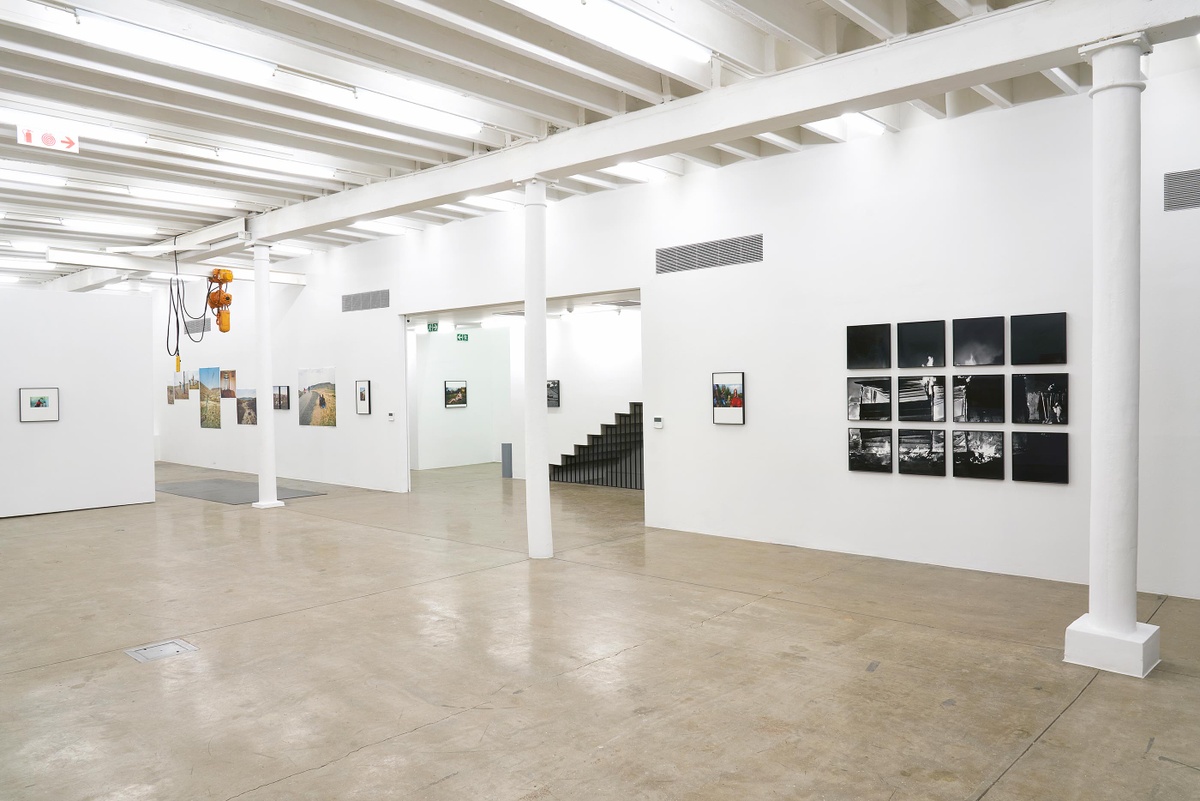 Installation photograph from the ‘Tell it to the Mountains’ exhibition in A4’s Gallery. On the right, Lindokuhle Sobekwa’s photographs ‘Jeannie with her sisters’ and ‘Shack of nyaope users is set on fire by an angry group of men that claim they stole their things. Nyaope users are always the first suspects in the communities’ are mounted on the wall.
