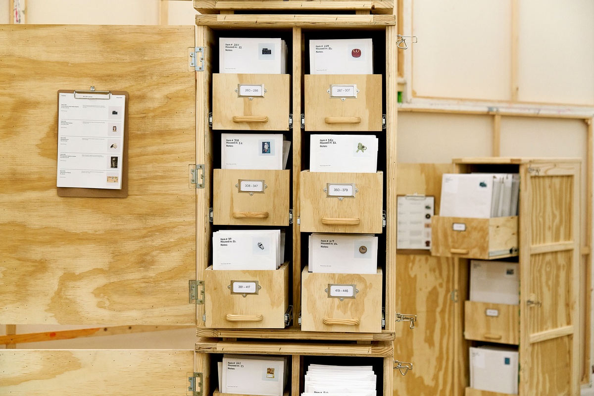 Installation photograph from the 'A Little After This' exhibition in A4 Arts Foundation's gallery that shows collected objects from Penny Siopis' 'Will' work organised in envelopes, which in turn are arranged in bespoke wooden filing cabinets.
