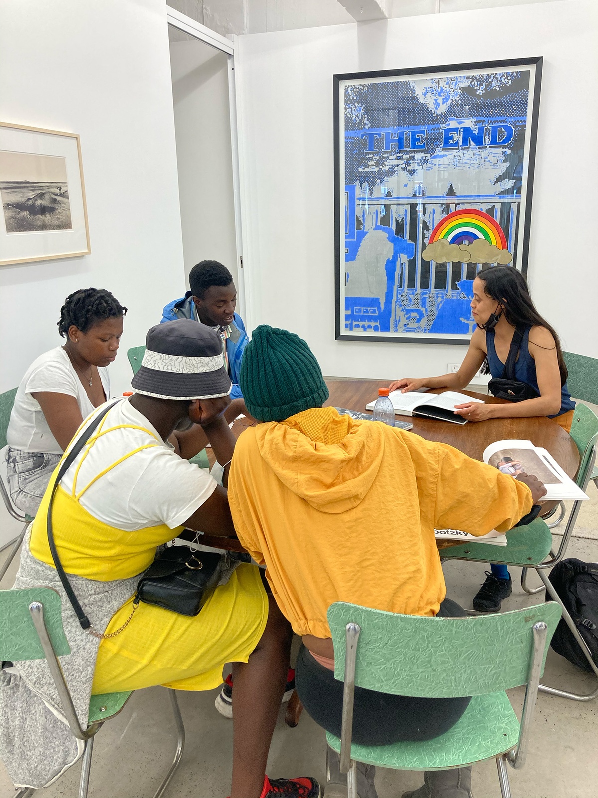 Event photograph from the ‘Lalela x A4' exchange during the ‘Tell It to the Mountains’ exhibition in A4’s Gallery. Lalela students and facilitators seated around a round wooden table in A4’s Reading Room.
