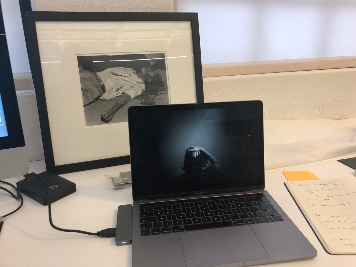 Process photograph from the offsite exhibition ‘Hay Tiempo, No Hey Tiempo’ at the Centro Fotográfico Álvarez Bravo, Mexico. At the front, a laptop sitting on a table display’s Jo Ratcliffe’s photograph ‘Microlite’. At the back, a framed print of Manuel Alvarez Bravo’s photograph ‘striking worker, assassinated’ leans against the wall at the back of the table.
