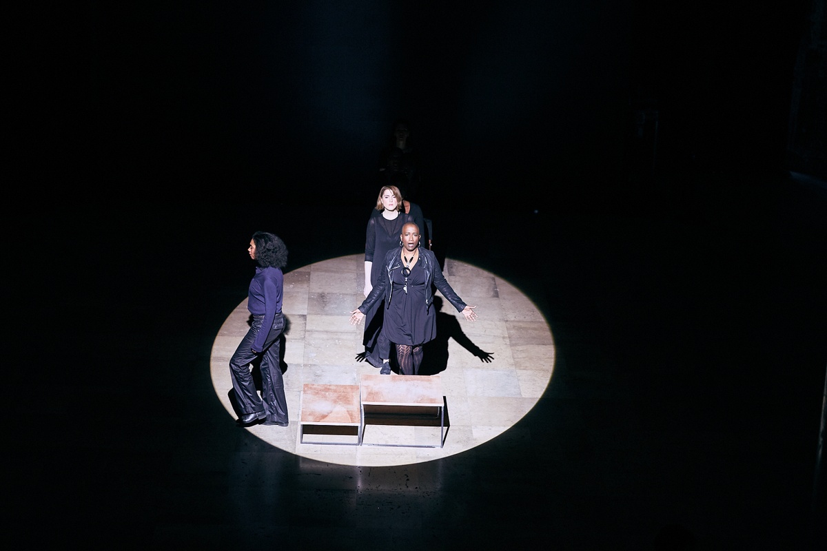 Event photograph from the offsite performance of ‘Elegy’ by Gabrielle Goliath at the D!STURB festival in Paris. A lineup of performers dressed in black stretches to a wooden podium with a performer standing on it in the middle.
