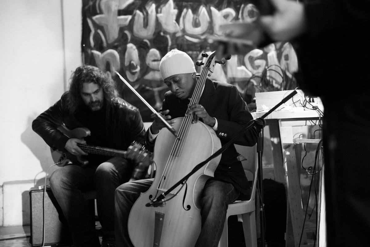 Process photograph from the ‘Future Nostalgia’ event with musician João Orecchia on A4’s first floor. On the left, Brydon Bolton sits with a bass guitar. In the middle, Thokozani Mhlambi sits with a baroque cello.
