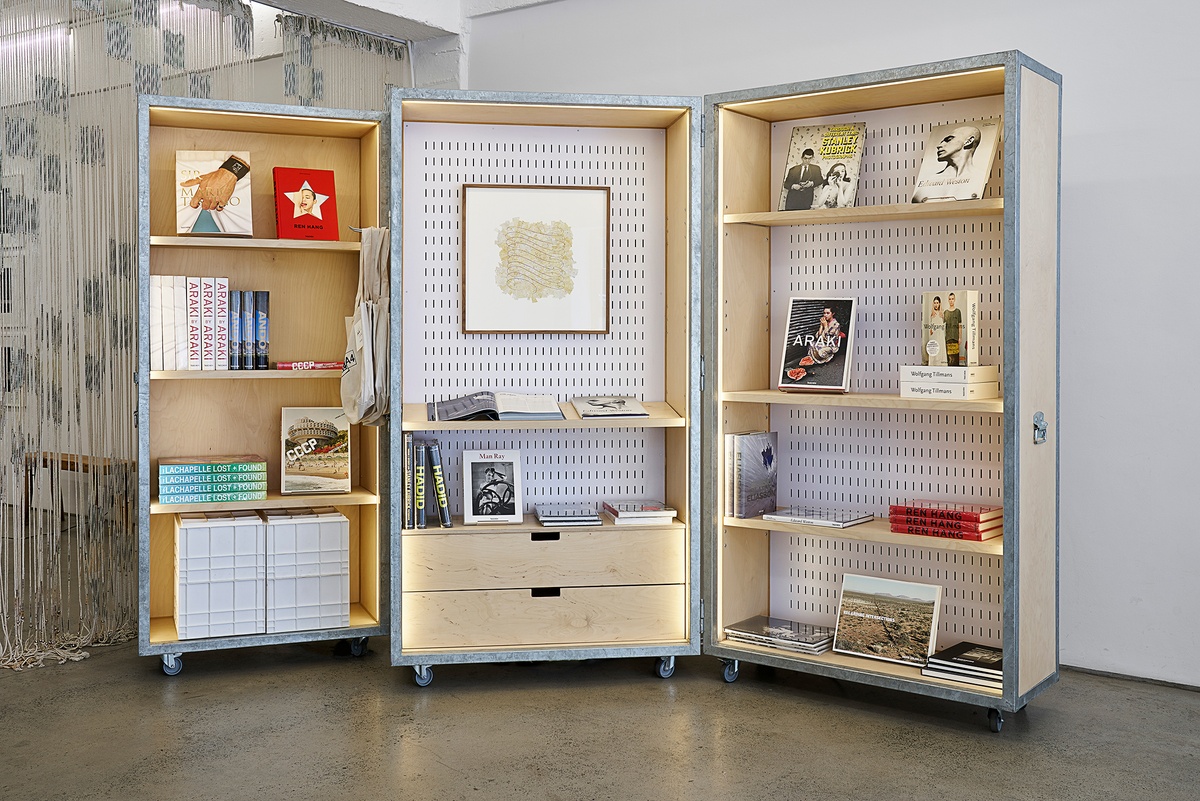 Installation photograph from the Taschen pop-up in A4’s Proto~ museum shop that shows a cabinet in A4’s foyer. On the left, Taschen’s ‘Sir Mario Testino’, ‘Ren Hang’ and ‘CCCP (Cosmic Communist Construction) - Chaubin’ publications are arranged on shelves. In the middle, Gerhard Marx’s collage and calligraphy work ‘Flourish I’ is mounted on the back of the cabinet, with Taschen’s ‘Man Ray’ publication on a shelf towards the bottom. On the right, Taschen’s ‘Through a different lens - Stanley Kubrick’, ‘Edward Weston, 1886-1958’, ‘Araki by araki’ and ‘Wolfgang Tillmans’ publications are arranged on the on shelves.
