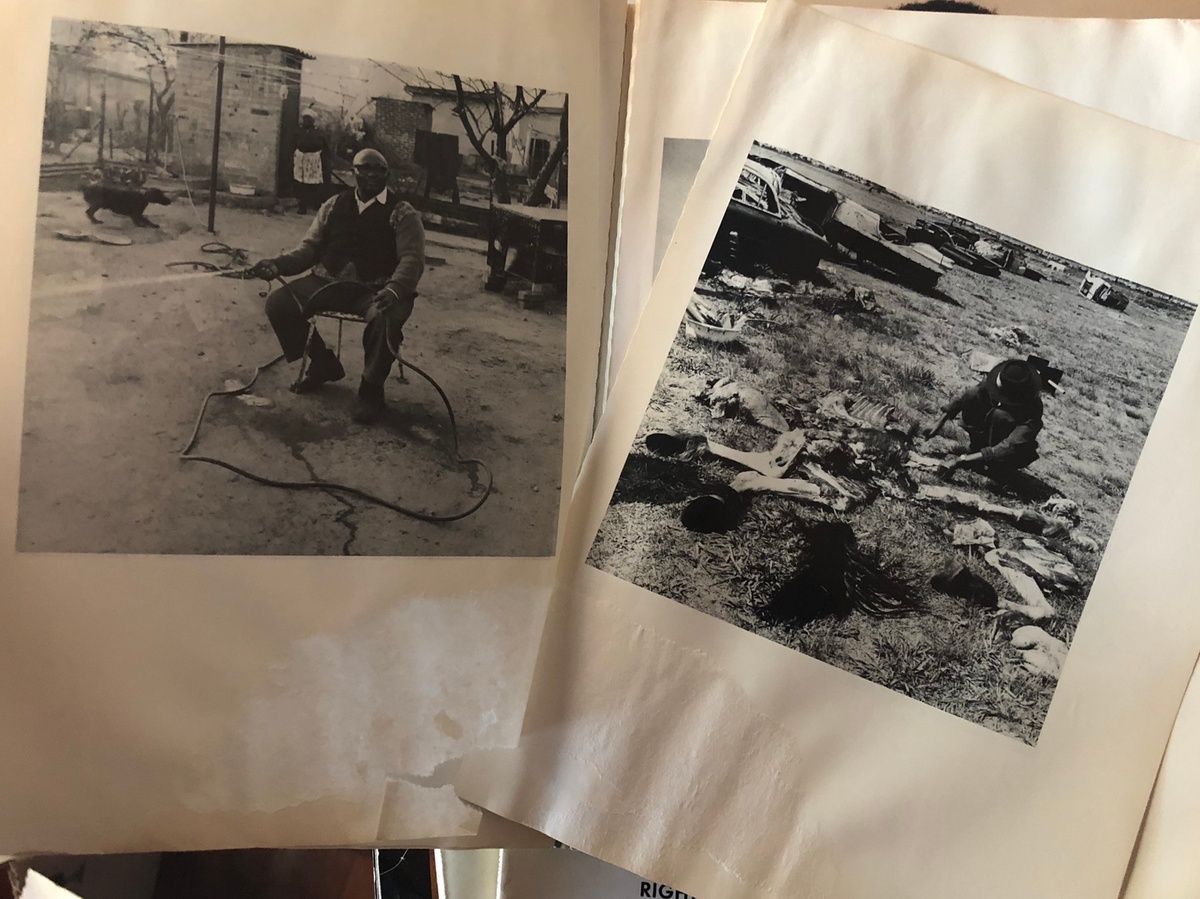 Process photograph from the ‘Picture Theory’ exhibition in A4’s Gallery that shows a closeup view of a 2 page spread from David Goldblatt and Nadine Gordimer’s ‘Lifetimes Under Apartheid’. On the left, Goldblatt’s monochrome photograph ‘Ephraim Zulu watering his garden, Central Western Jabavu, Soweto, 1972’. On the right, Goldblatt’s photograph ‘Butchering the horse of a coal merchant for the sale of its meat, Tladi, Soweto, 1972’.
