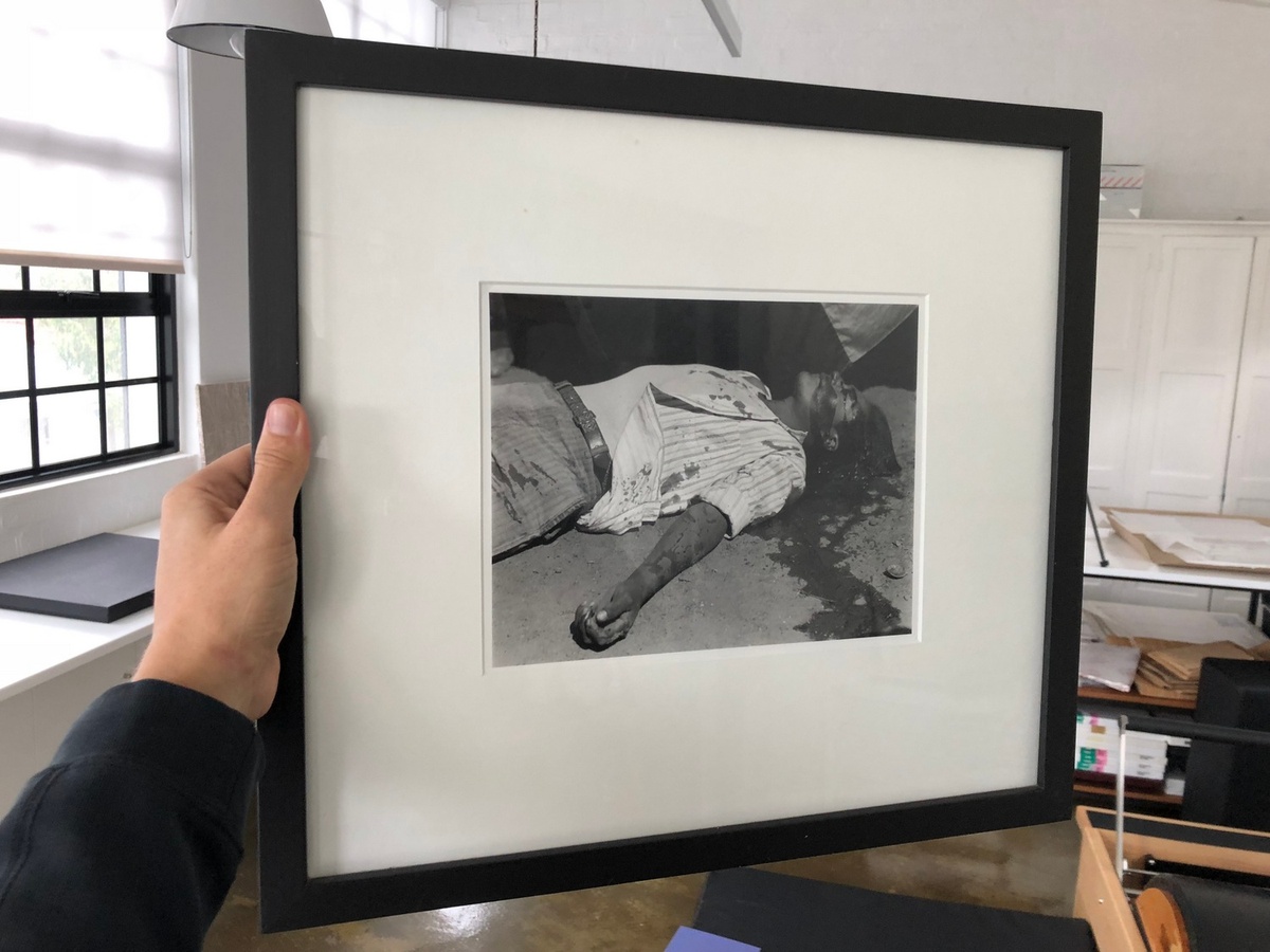 Process photograph from the offsite exhibition ‘Hay Tiempo, No Hey Tiempo’ at the Centro Fotográfico Álvarez Bravo, Mexico. A hand holds a framed print of Manuel Alvarez Bravo’s photograph ‘striking worker, assassinated’.
