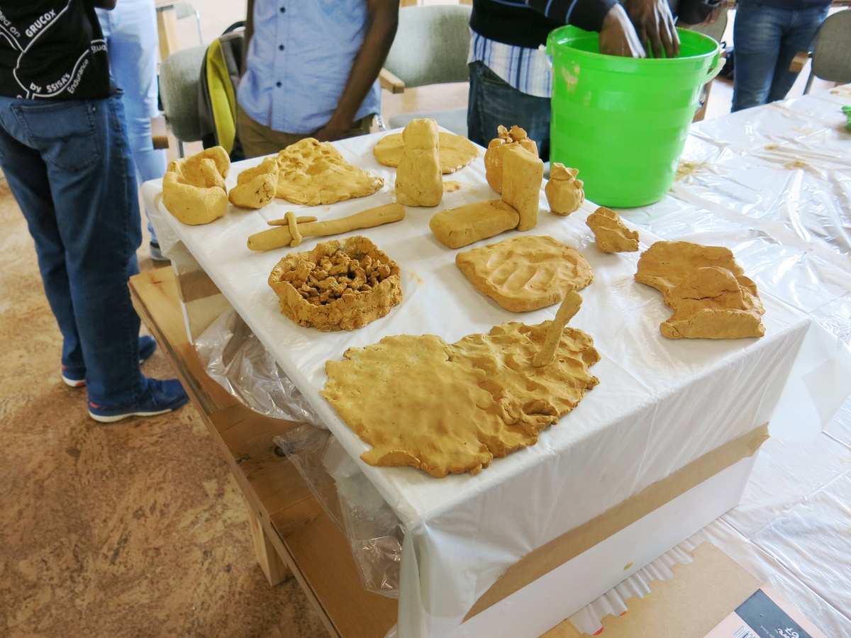 Event photograph from the 2018 rendition of the City Research Studio exchange with the African Centre for Cities. In the middle, a table covered in white plastic sheeting holds various clay forms.
