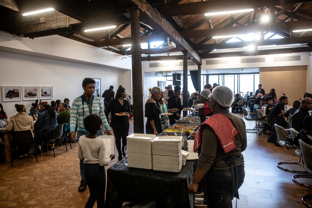 Event photograph from the opening of the “Ikhono LaseNatali” exhibition in A4’s Gallery shows attendees dishing food from a buffet on A4’s top floor.
