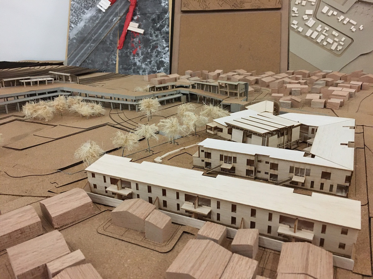 Photograph of an artwork from the Masters of Architecture Graduate Exhibition on A4’s top floor that consists of a cardboard model that depicts topography and buildings.
