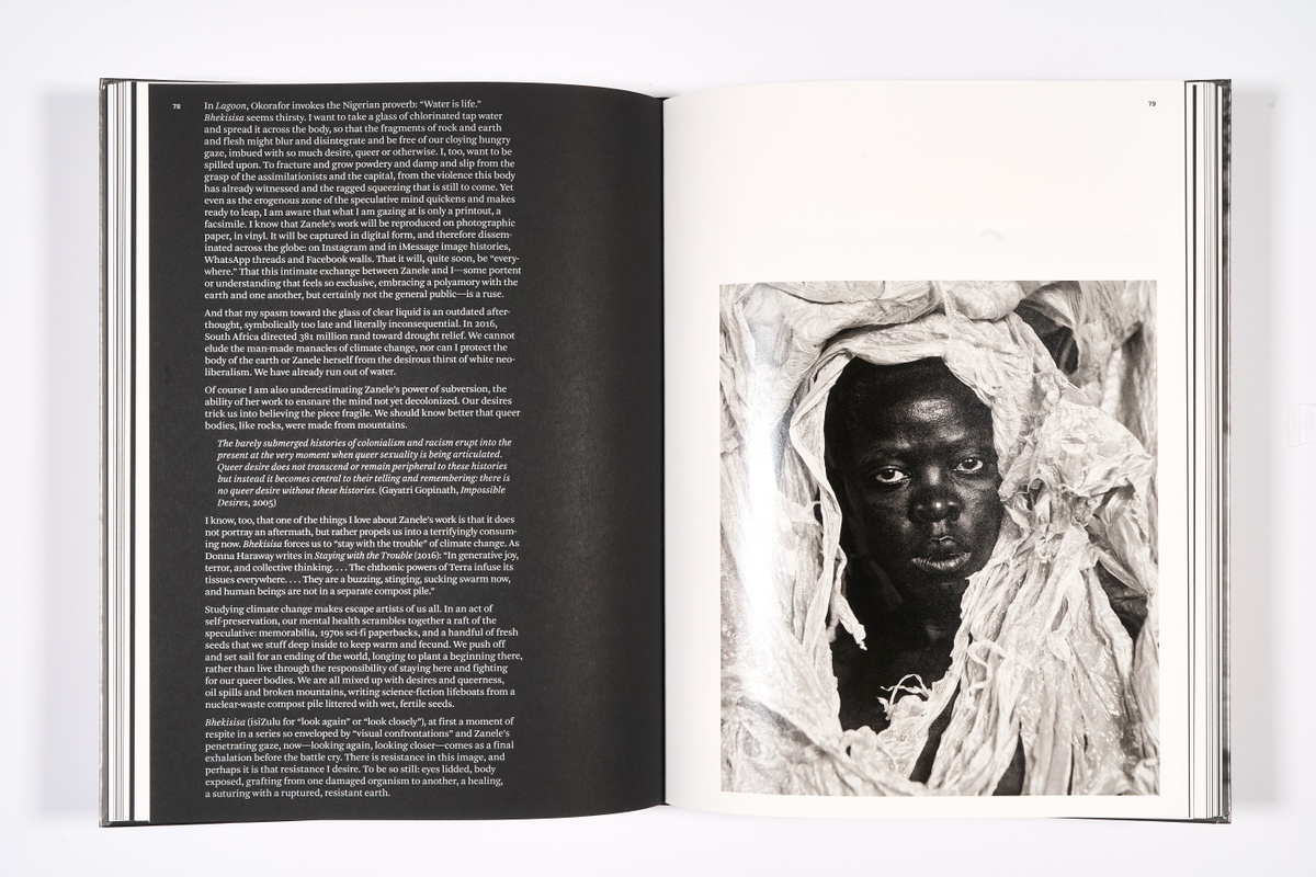 A topdown photograph of a 2-page spread from Zanele Muholi's photo-book 'Somnyama Ngonyama: Hail the Dark Lioness' on a white background.
