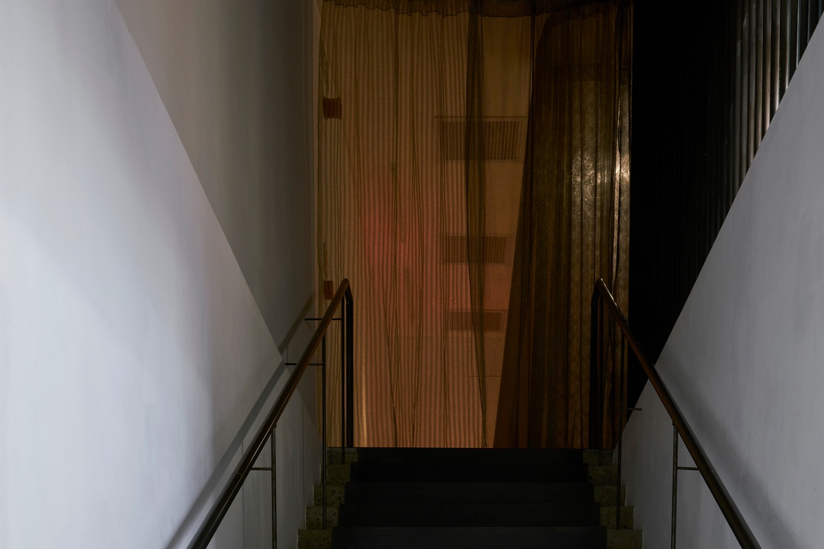 Installation photograph from the ‘Risk’ exhibition in A4’s Gallery. In the middle, Igshaan Adam’s site-specific fabric installation sits at the top of the gallery staircase.
