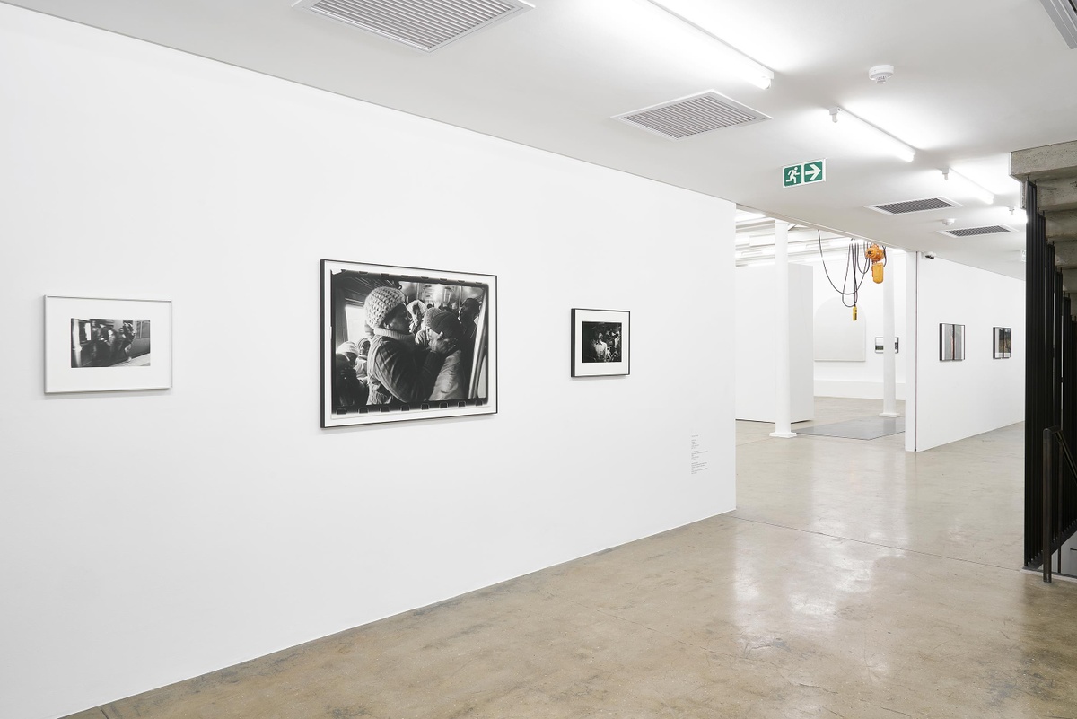 Installation photograph from the ‘Tell it to the Mountains’ exhibition in A4’s Gallery. On the left, Ernest Cole’s untitled monochrome photograph, Santu Mofokeng’s monochrome photograph ‘Supplication, Johannesburg-Soweto Line’ and David Goldblatt’s monochrome photograph ‘Going home: Marabastad-Waterval route: for most of the people in this bus, the cycle will start again tomorrow at between 2 and 3 am. 1984’ are mounted on the wall.
