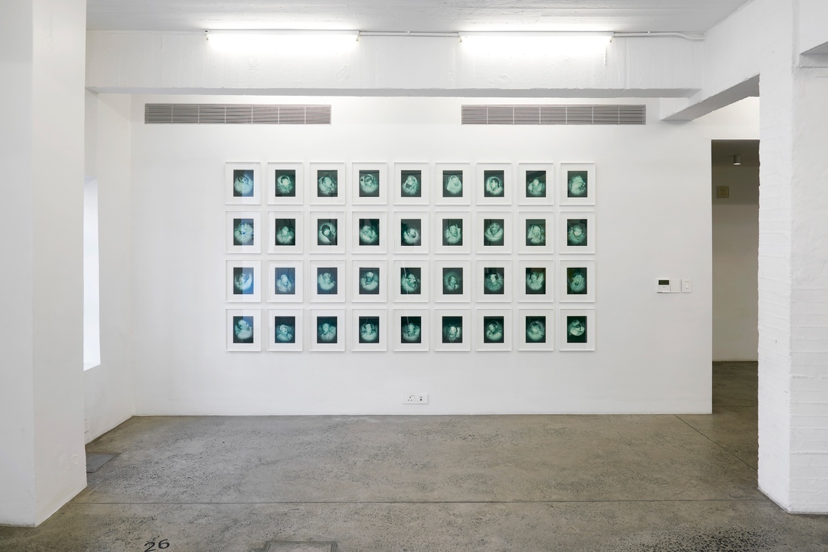 Installation photograph from the ‘Risk’ exhibition in A4’s Gallery. In the middle, Pieter Hugo’s photographic series ‘The Journey’, 36 photographs in a 9 by 4 grid, is mounted on the ground floor wall.
