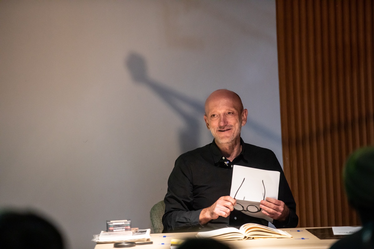 Event photograph from the book launch of 'ArtThrob: 25 Years of Art Writing in South Africa' in A4 Arts Foundation that shows writer Sean O'Toole seated at the speakers' table, addressing the attendees.
