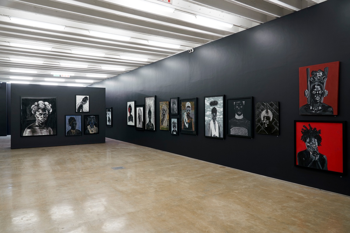 Installation photograph from the “Ikhono LaseNatali” exhibition in A4’s Gallery. On the left, a black moveable gallery wall lined with various artworks. On the right, a black gallery wall lined with various artworks.
