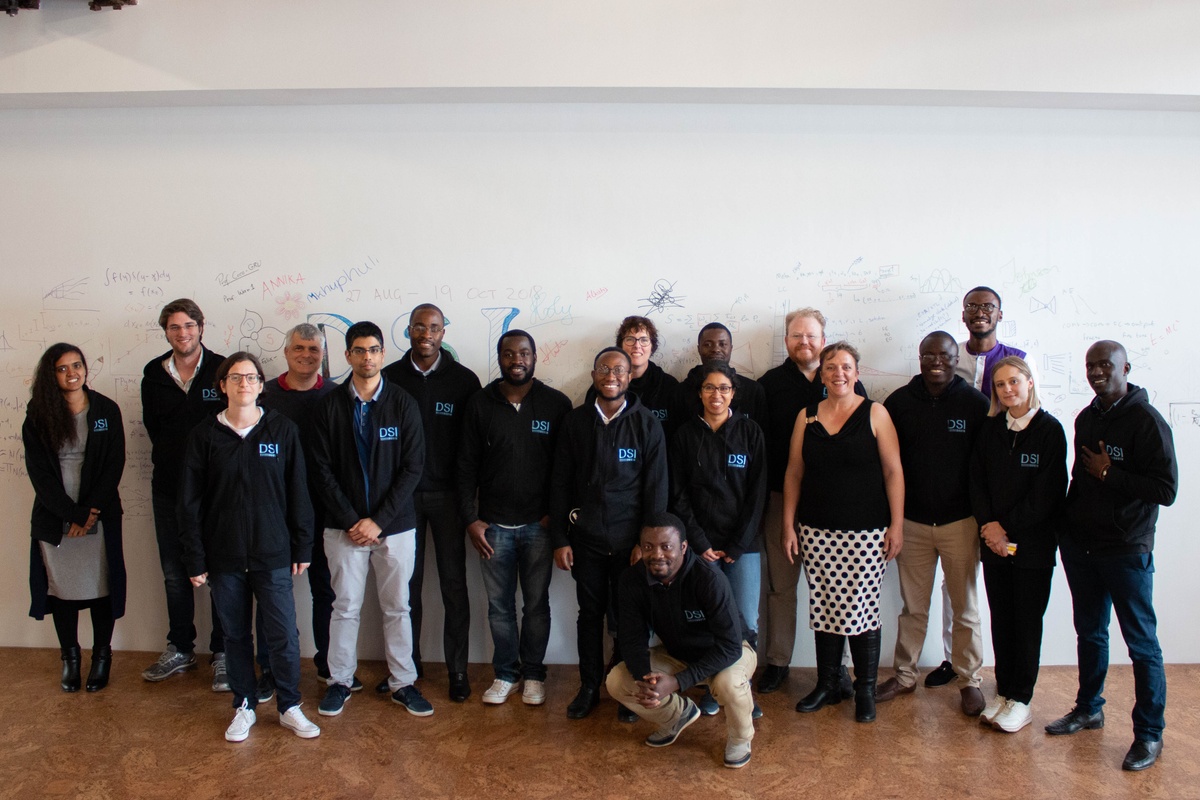 Process photograph from the ‘Data Science Intensive’ event with the AIMS Institute for Mathematical Sciences on A4’s top floor that shows participants standing in front of a white wall with writing and drawings in felt pen marker.
