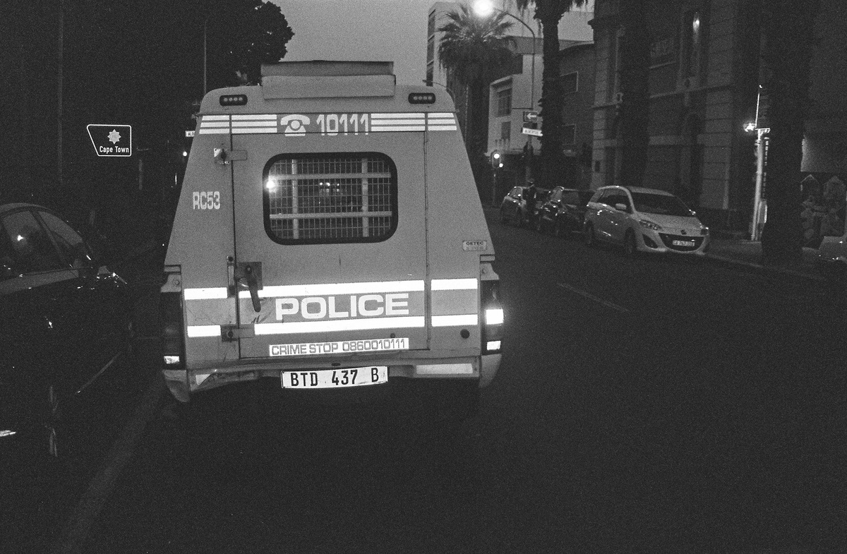 Monochrome event photograph from ‘Contact’, a collaboration between A4’s proto~ museum shop and Oath Magazine, taken by a participant that shows the back of a parked police van.
