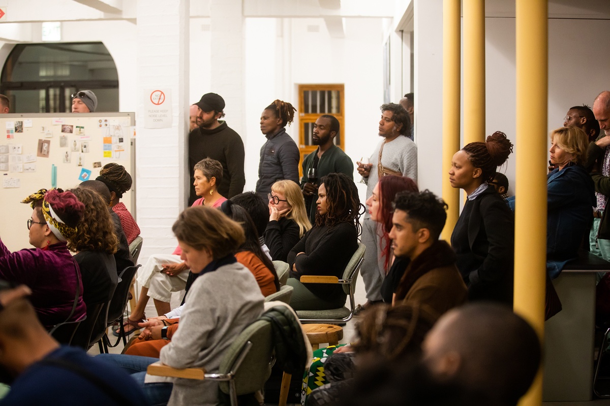 Event photograph from ‘Bare in Conversation with Sir Professor Zanele Muholi’, Session 1 of the ‘Bare Stories’ series hosted on A4’s ground floor that depicts attendees seated and standing.
