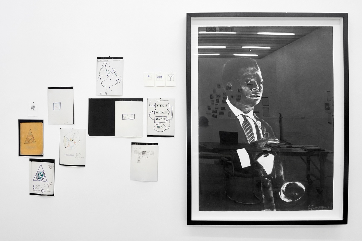 Installation photograph from the 2018 rendition of ‘Parallel Play’ in A4’s Gallery. On the left, photocopies of notebook pages with drawings are pasted onto the gallery wall. On the right, Sam Nhlengethwa’s framed charcoal drawing ‘Portrait of Miles Davis’ is mounted on the gallery wall. 
