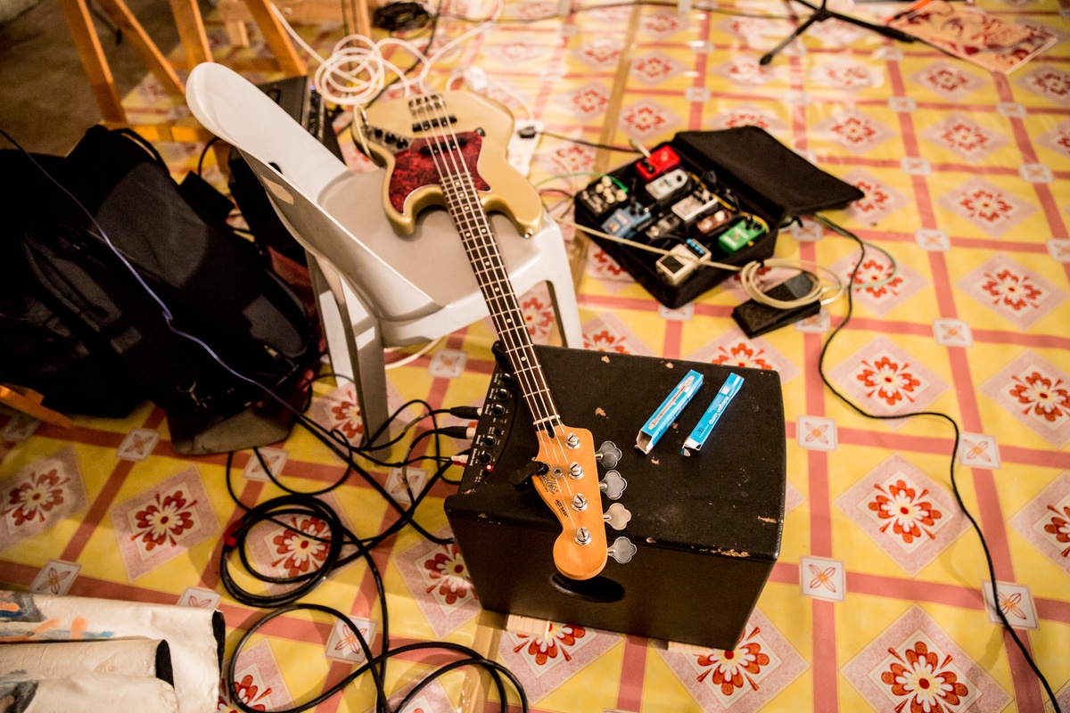 Process photograph from the ‘Future Nostalgia’ event with musician João Orecchia on A4’s first floor. A plastic chair on patterned laminate flooring holds a bass guitar, along with a amplifier and a pedal board.
