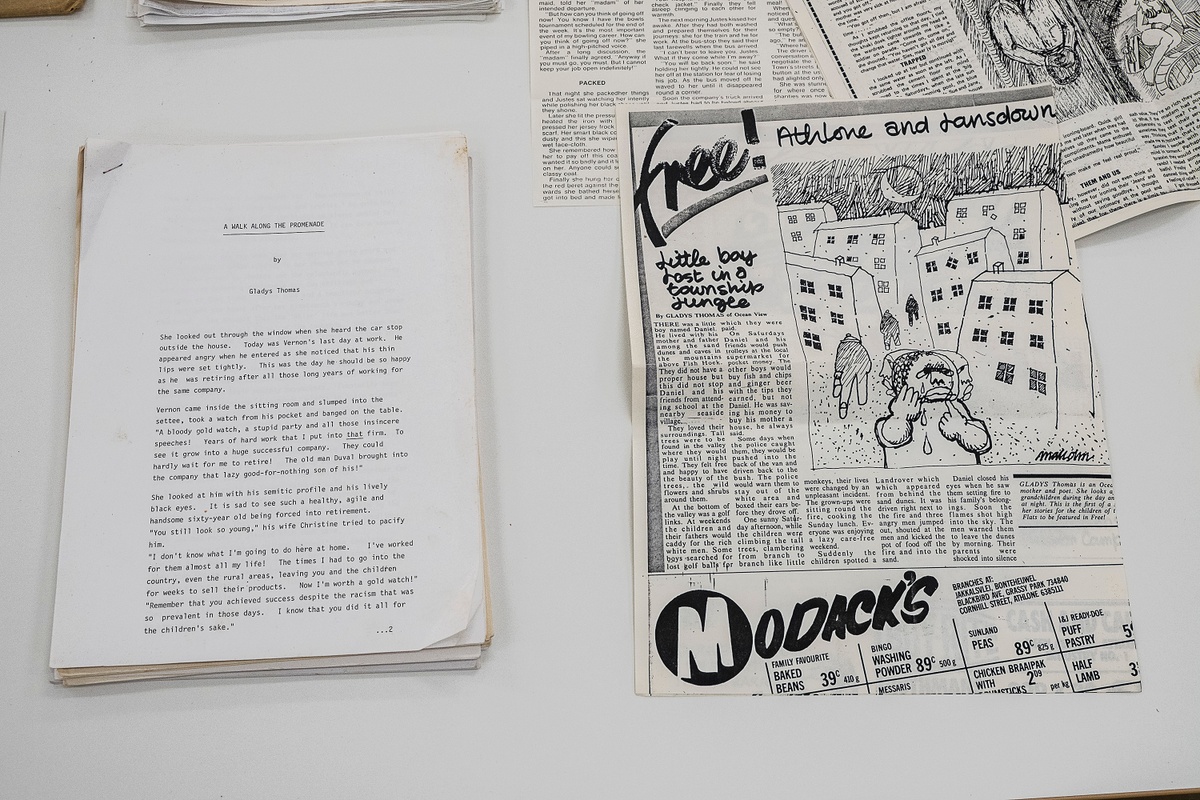 Installation photograph from the ‘Gladiolus’ exhibition on A4’s ground floor that shows printed matter arranged on a table. On the left, a stapled copy of Gladys Thomas’ ‘A walk along the promenade’. On the right, a photocopy of Thomas’ short story ‘Little boy lost in a township jungle’.
