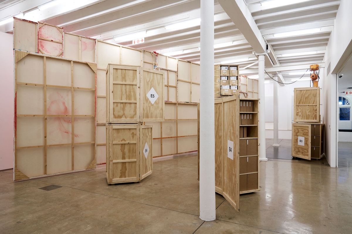 Installation photograph from the 'A Little After This' exhibition in A4 Arts Foundation's gallery. At the back, the back of an installation of Penny Siopis' glue, ink and oil 'Maitland' paintings suspended from the ceiling. In the front, collected objects from Penny Siopis' 'Will' work are stored in envelopes and wooden crates. 
