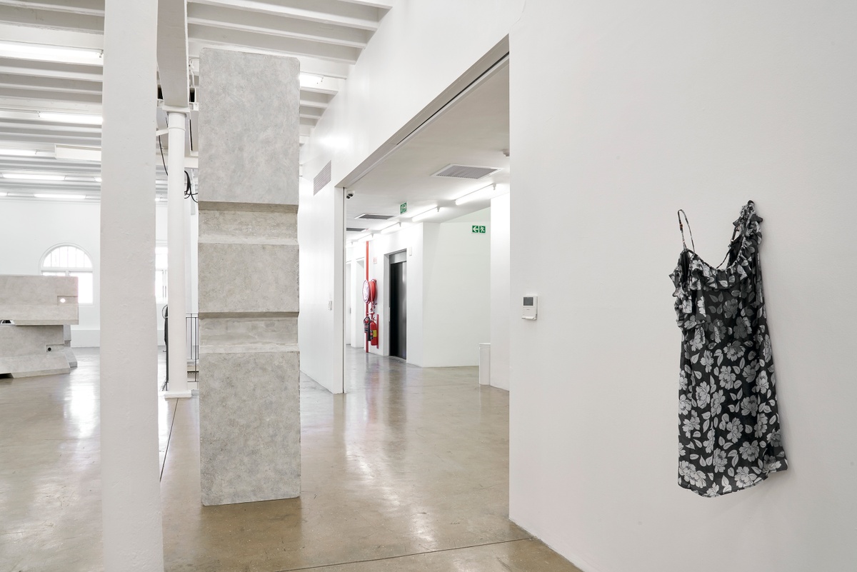 Installation photograph from the ‘without a clear discernible image’ exhibition in A4’s Gallery. On the left, Kevin Beasley’s untitled plywood and paint sculpture stands on the gallery floor. On the right, Beasley’s untitled sculpture consisting of a resin hardened housedress is mounted on the gallery wall.
