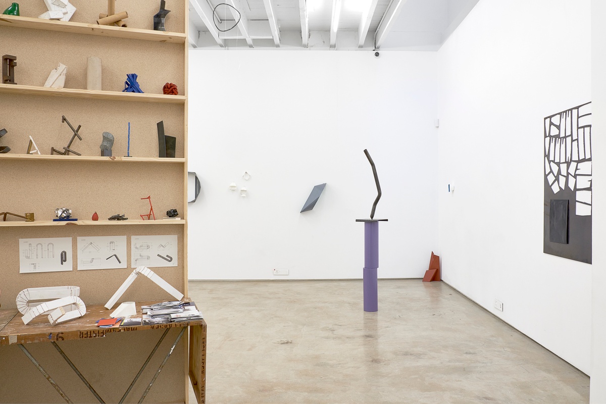 Installation photograph from the 2018 rendition of ‘Parallel Play’ in A4’s Gallery that shows Kyle Morland’s sculptural objects sitting on a freestanding wooden shelf on the left and on the gallery floor and walls on the right.
