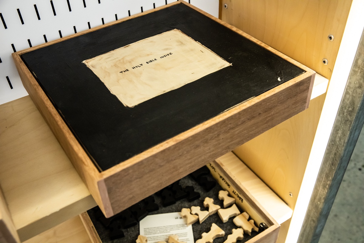 Event photograph from the launch of Brett Seiler’s chess set in A4’s Proto museum shop that shows one of Seiler's chess sets sitting in a cabinet, with the drawing on the reverse of the board angled towards upwards.
