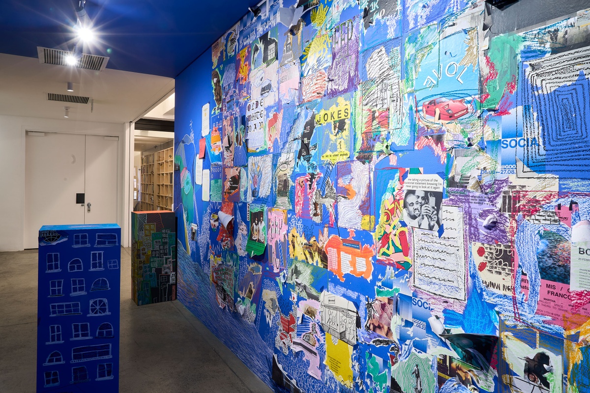 Installation photograph from ‘Disruption’, Hanna Noor Mahomed’s residency in A4’s Goods project space. On the right, a wall mural with drawings and collaged graphic material from Khanya Mashabela’s ‘Social’ archive. On the left, a blue plinth covered in chalk drawings.

