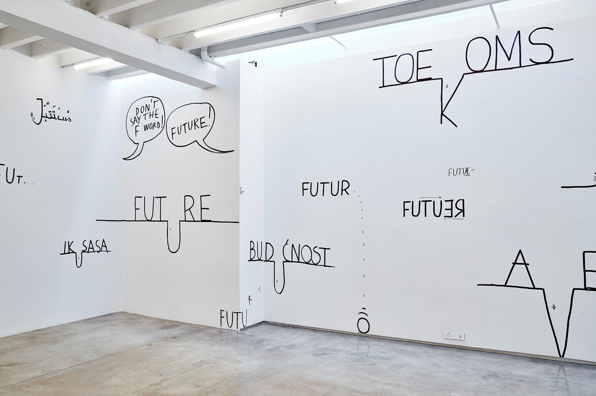 Installation photograph from Dan Perjovschi’s ‘The Black and White Cape Town Report’ exhibition in A4’s Gallery. The gallery walls holds several translations of the word ‘future’ on top of lines, where one character is dropped into the line so as to resemble a geographic feature.
