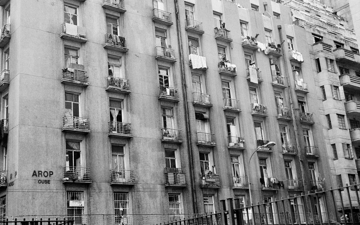 Monochrome photograph ‘AROP HOUSE’ from Sabelo Mlangeni’s residency on A4’s top floor that shows a building front with rows of balconies.
