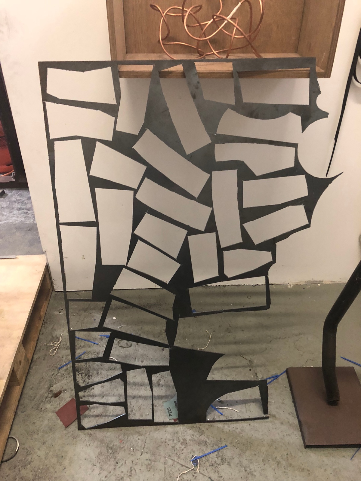 Process photograph from the More For Less exhibition in A4’s Gallery that depicts a sheet of metal with multiple cutouts by Kyle Morland.
