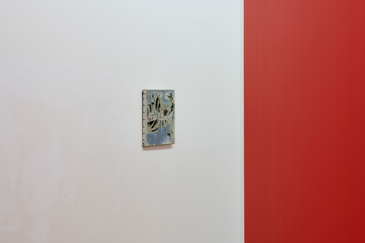 Installation photograph from the 'A Little After This' exhibition in A4 Arts Foundation's gallery. On the left, Gerard Sekoto's oil on canvas painting 'Le Pont St. Michel' mounted on a white gallery wall. On the right, the corner of a large red wooden box from Alex Da Corte's video installation 'ROY G BIV'.
