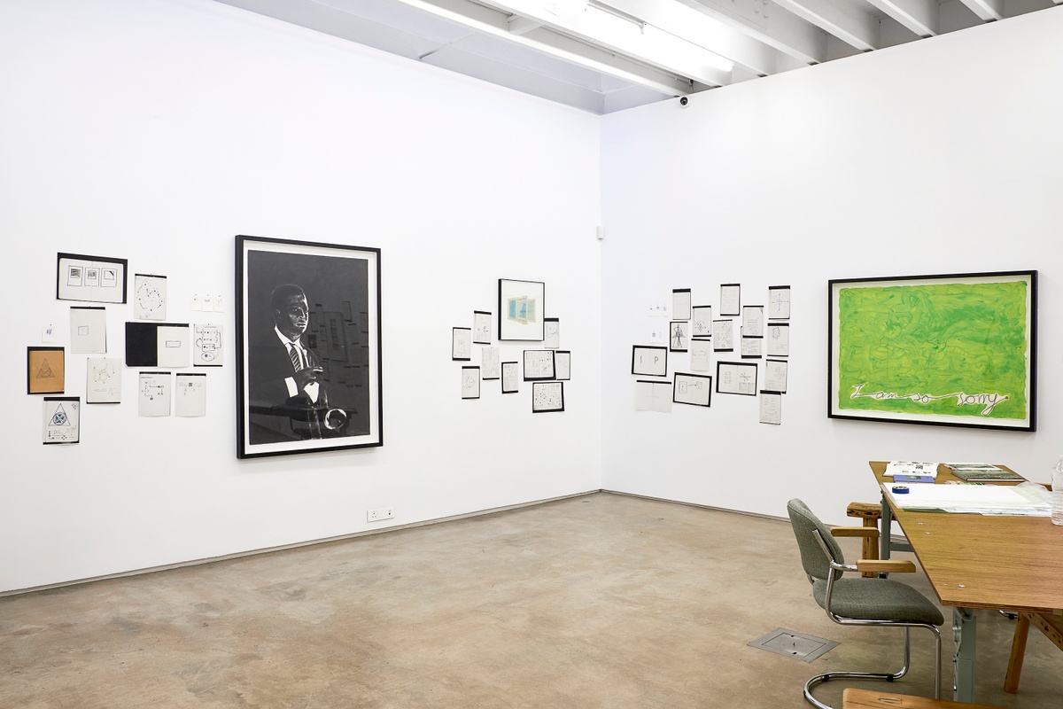 Installation photograph from the 2018 rendition of ‘Parallel Play’ in A4’s Gallery. On the left, Sam Nhlengethwa’s charcoal drawing ‘Portrait of Miles Davis’ is mounted on the gallery wall, along with photocopies from a notebook. On the right, Moshekwa Langa’s gouache and pencil work ‘I Am So Sorry (Green)’ is mounted on the gallery wall, along with photocopies from a notebook.
