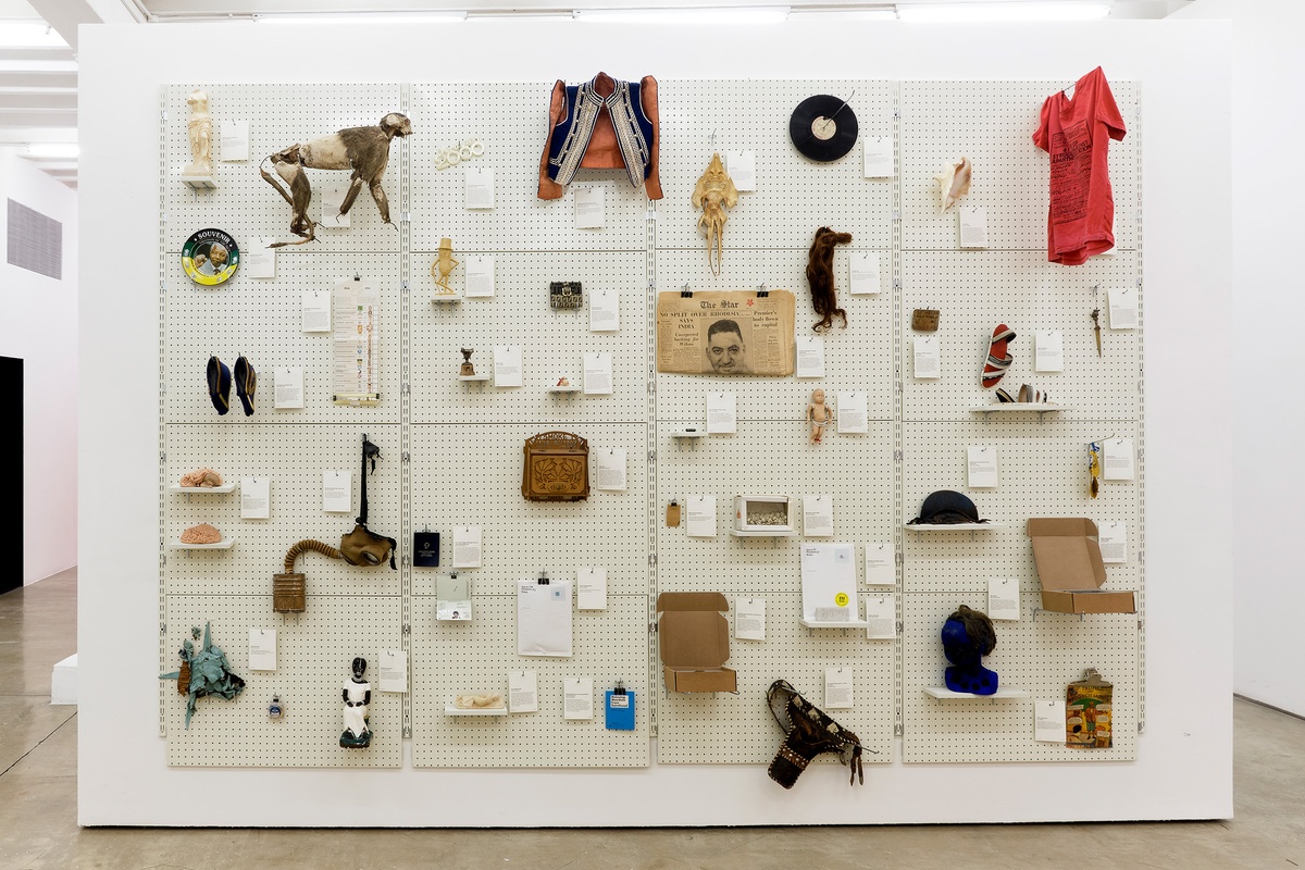 Installation photograph from the 'A Little After This' exhibition in A4 Arts Foundation's gallery that shows collected objects from Penny Siopis' 'Will' work mounted on a white moveable gallery wall through the use of perforated metal panels.
