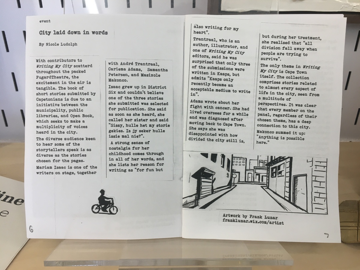 Photograph of the ‘OBZine’ publication from the 2019 rendition of the Open Book Literary Festival, with contributions from various student writers. A two-page spread features Nicole Ludolph’s text ‘City laid down in words’, with drawings of a person riding a bicycle and a city street.
