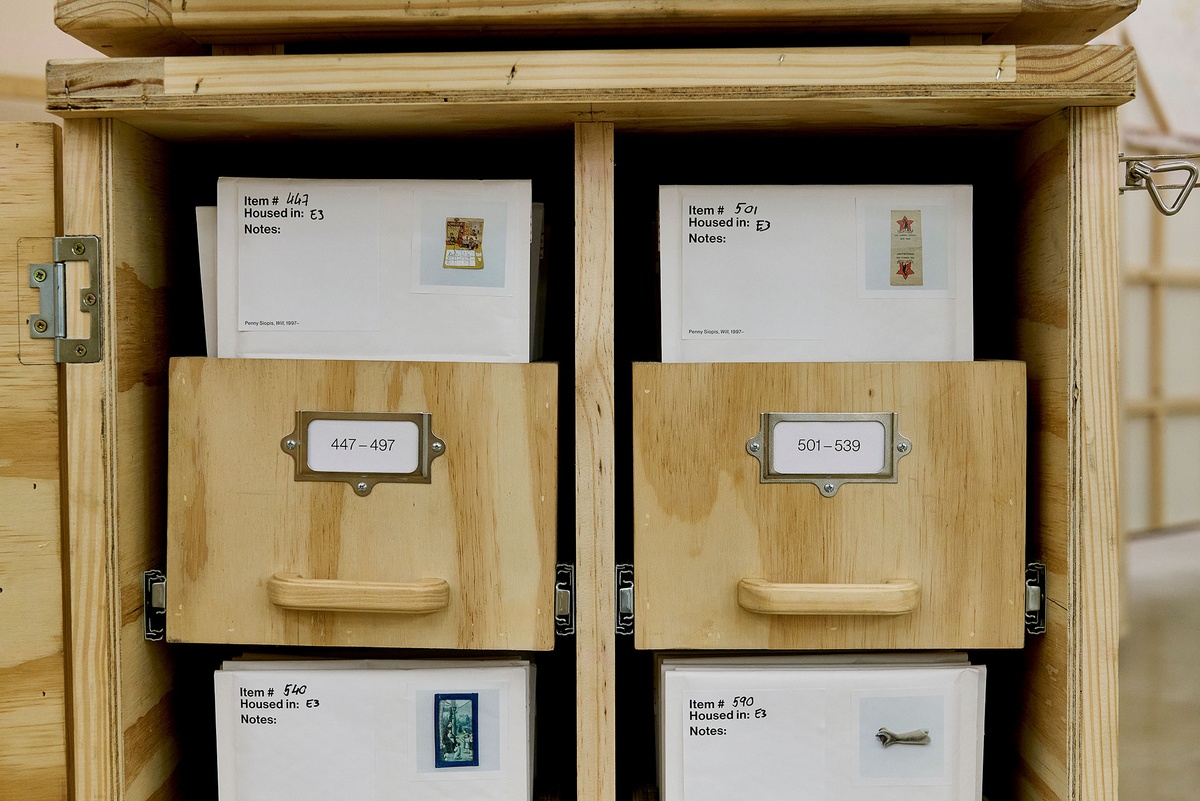 Installation photograph from the 'A Little After This' exhibition in A4 Arts Foundation's gallery that shows collected objects from Penny Siopis' 'Will' work organised in envelopes, which in turn are arranged in bespoke wooden filing cabinets.
