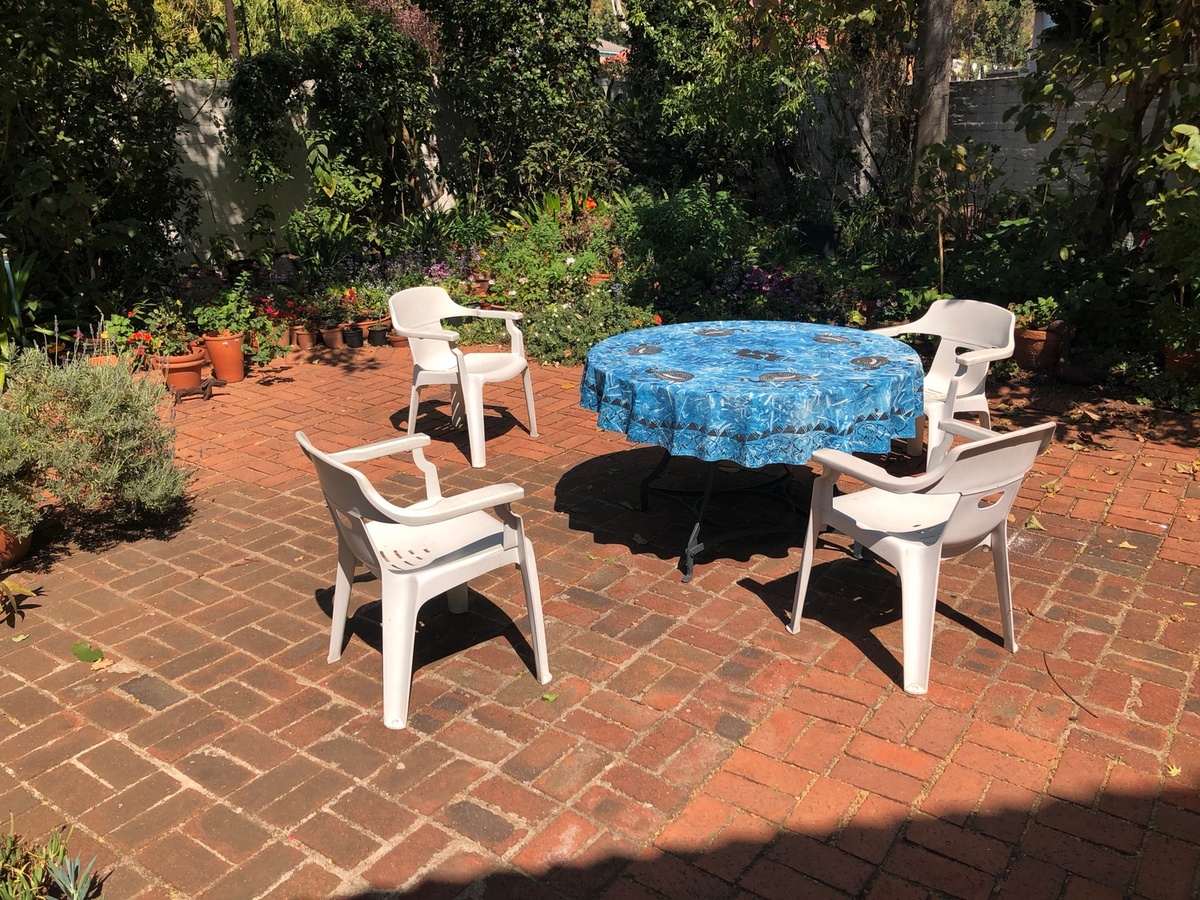 Process photograph from the ‘Picture Theory’ exhibition in A4’s Gallery that depicts a table and chairs in a garden with brick paving.
