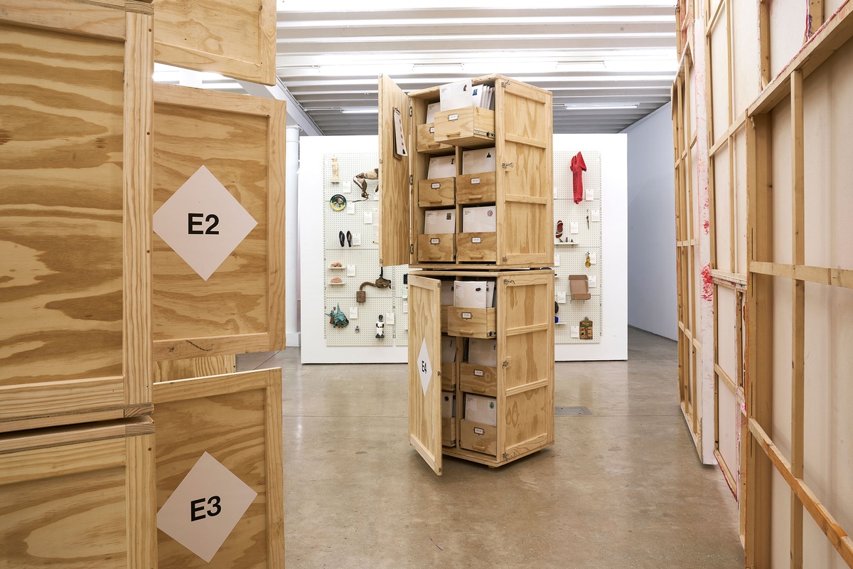 Installation photograph from the 'A Little After This' exhibition in A4 Arts Foundation's gallery that shows collected objects from Penny Siopis' 'Will' work. At the front, objects are arranged in envelopes and bespoke wooden filing cabinets. At the back, objects mounted on a white moveable gallery wall through the use of perforated metal panels.

