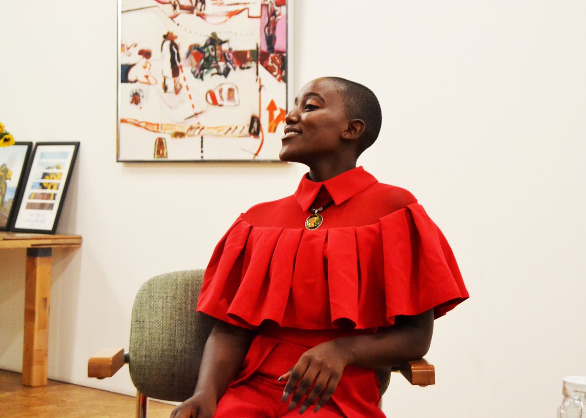 Event photograph from book launch of ‘The Truth Shall Bloom’ by Tabogo Nong on A4’s top floor. At the back, Robert Hodgins’ oil painting ‘Downtown’ is mounted on a white wall. At the front, Nong sits on a chair.
