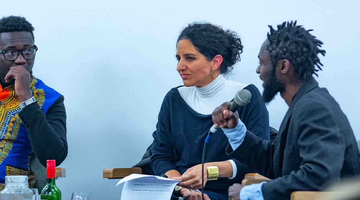 Event photograph from the 2018 rendition of the Open Book festival on A4’s ground floor. At the back, three panelists are seated with microphones.
