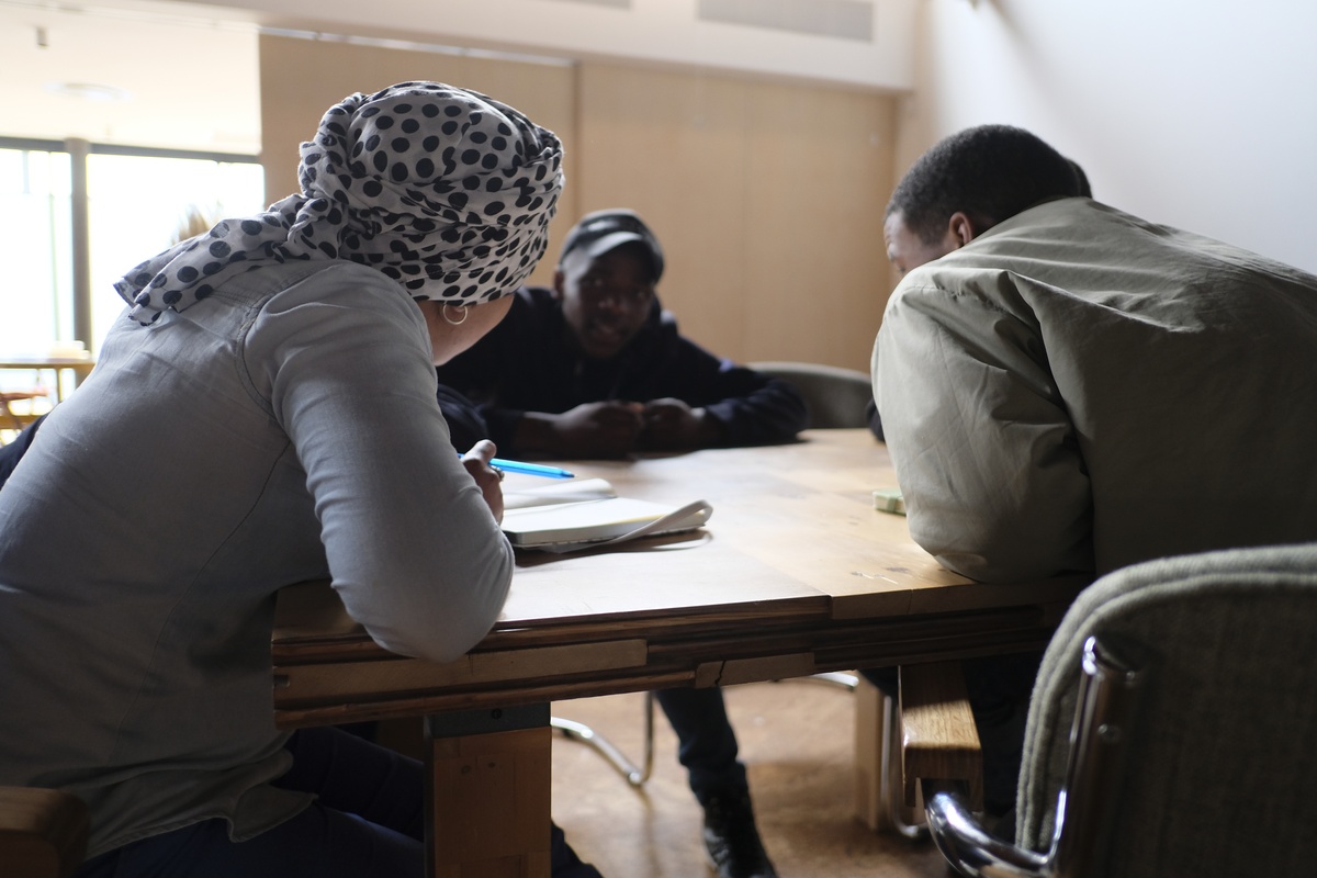 Event photograph from the ‘Youth, Identity and the City’ exchange on A4’s top floor. Three young people are seated around a wooden table.
