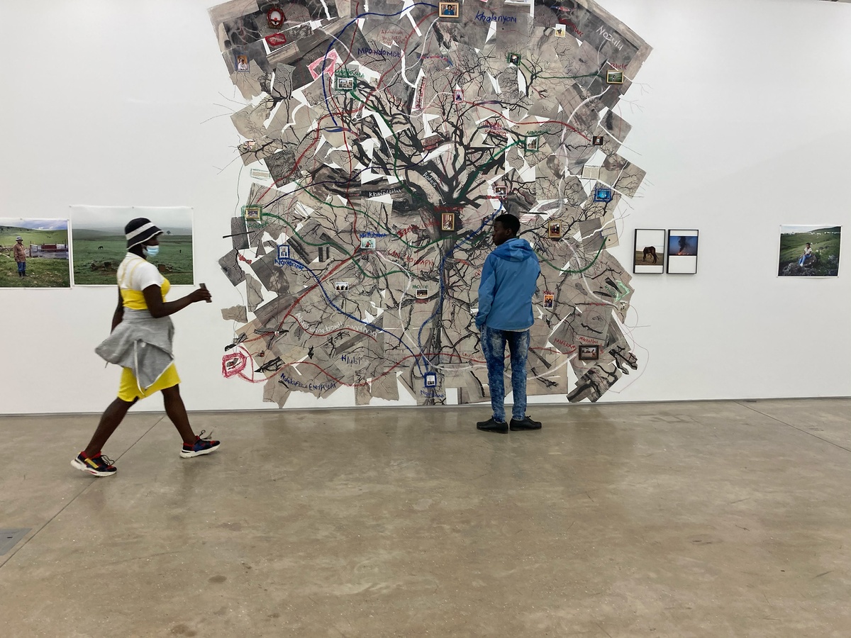 Event photograph of students from the Lalela educational programme interacting with the ‘Tell It to the Mountains’ exhibition in A4’s Gallery. At the back, Lindokuhle Sobekwa’s photographic collage ‘Mthimkhulu II’ occupies the white gallery wall.
