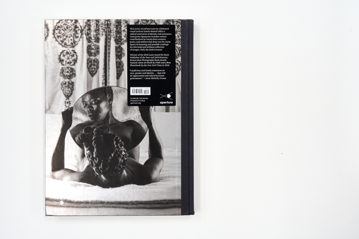 A topdown photograph of the back cover of Zanele Muholi's photo-book 'Somnyama Ngonyama: Hail the Dark Lioness' on a white background.
