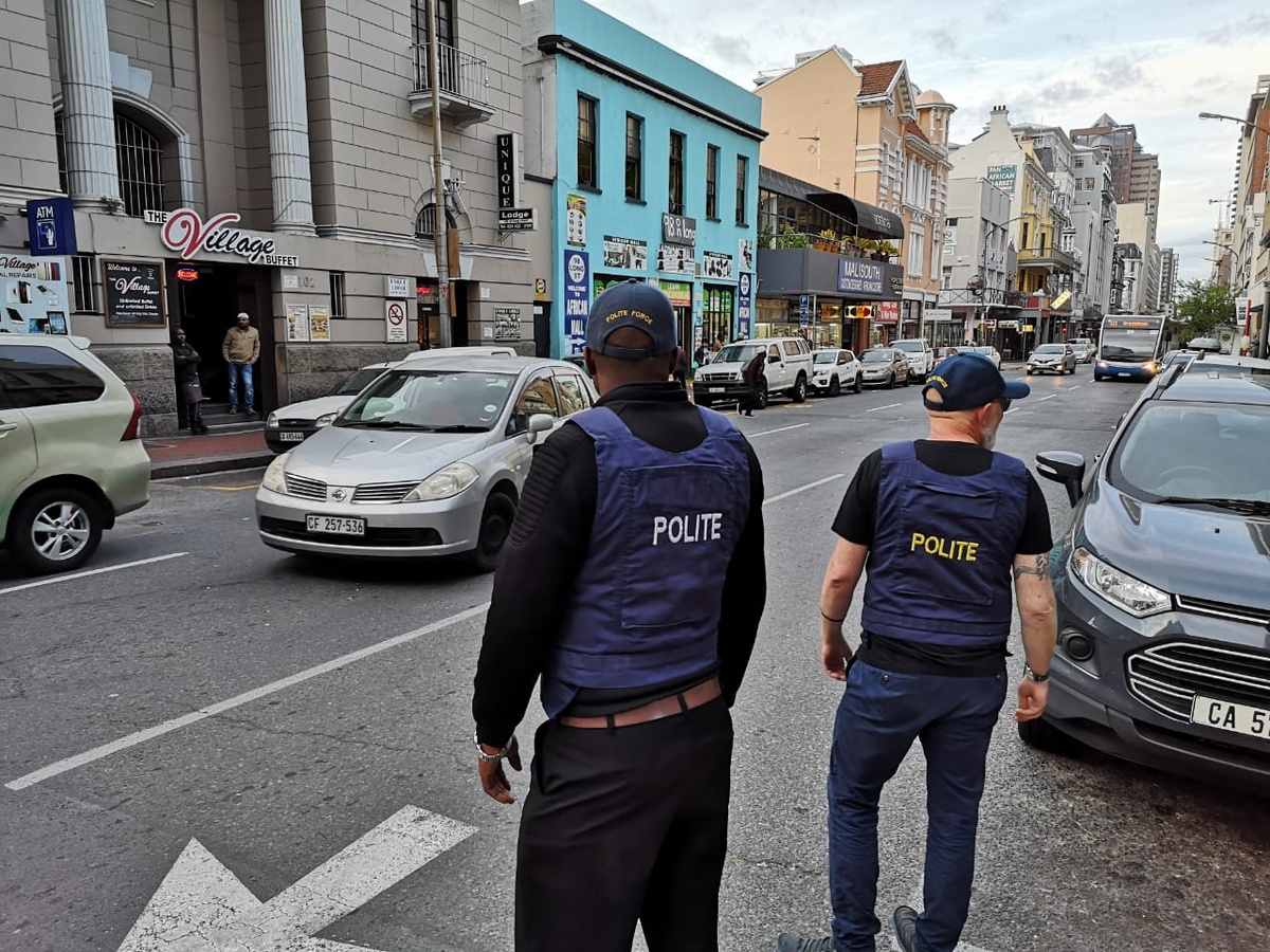 Process photograph from the 2019 rendition of Christian Nerf’s performance piece ‘Polite Force.’ Two participants dressed in ‘Polite Force’ riot gear waiting to cross a street.
