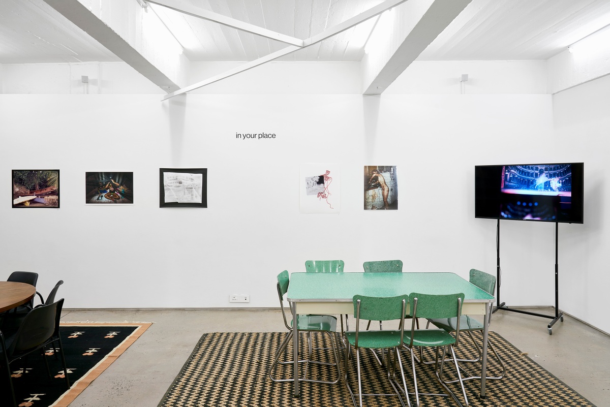 Installation photograph from the ‘In Your Place’ exhibition on A4’s ground floor. On the left, Freddie L. Rankin II’s photograph ‘Untitled 1 - The Isle of Flowers, 1848’, Avijit Halder’s photograph ‘Building the Fort’ and Samantha Box’s print ‘Map #1’ are mounted on the wall. In the middle, Pippa Hetherington’s collage ‘The Rest Is Memory #1’ and Lily Mott’s print ‘Housewife’ are mounted on the gallery wall. On the right, Eugene Lee’s video ‘Untitled (not so keyword)’ is displayed on a freestanding screen.
