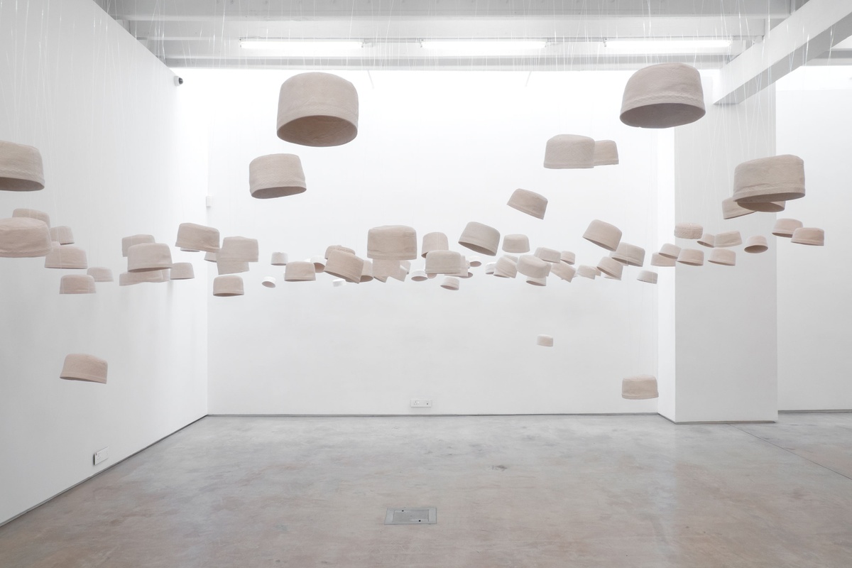 An installation photograph of Haroon Gunn-Salie and James Mathews' installation 'Amongst Men' shows casts of kufiyas suspended from the ceiling.
