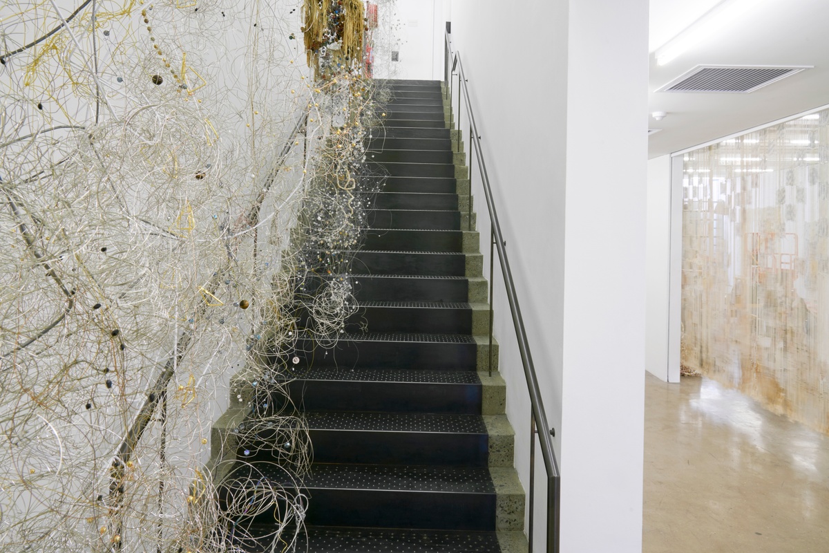 Process photograph from ‘Open Production’, Igshaan Adams’ hybrid studio/exhibition in A4’s Gallery. On the left, the gallery staircase hosts mixed media sculptures suspended from the ceiling.
